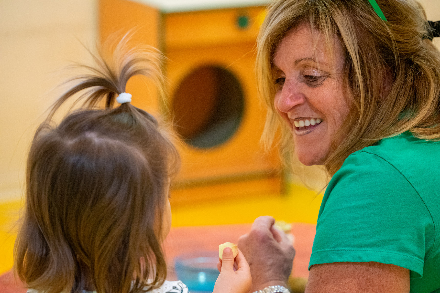Une éducatrice souriant à un enfant de la crèche